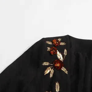 Close-up detail of heavy-duty 3D floral patches and gold leaf beading on black blazer