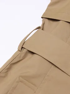 Detailed macro shot showing the waist belt loop and twill fabric of a khaki trench coat.