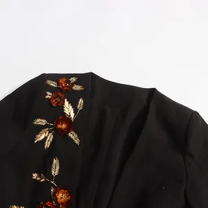 Macro detail of intricate 3D amber floral and gold bead embroidery on a black blazer