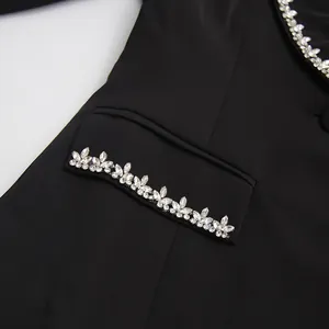 Elegant close-up of crystal flower embellishments on a stylish black blazer pocket flap