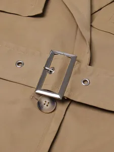 Detailed macro view showing the belt buckle and high-quality fabric texture of a tan trench coat