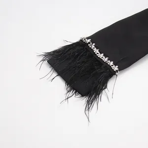 Detail of luxury blazer sleeve featuring rhinestone flowers and black feather trim