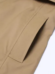 Close-up detail of khaki trench coat pocket with precise stitching and texture