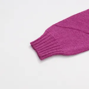 Detailed close-up of the ribbed cuff and knit texture of a magenta pullover sweater.