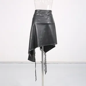 Detail view of an irregular black faux leather skirt with delicate lace trim and asymmetric hem.