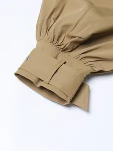 Close-up detail of khaki trench coat cuff with gathers and adjustable strap.