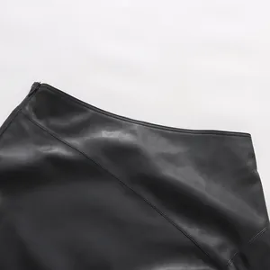 Detail view of asymmetrical waistline and side zipper on black faux leather skirt