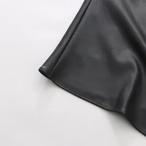 Close-up of the fine texture and neat stitching on a black faux leather skirt hem.
