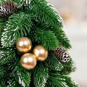 Detailed view of a mini artificial Christmas tree with golden baubles and pine cones