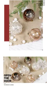 Dettaglio di eleganti palline di Natale dipinte con motivi dorati su sfondo di iuta rustica.