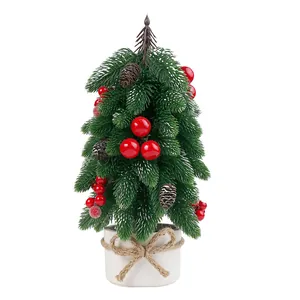 Mini artificial tabletop Christmas tree with red berries and pine cones in a white pot