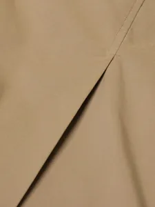 Detailed macro shot of khaki trench coat fabric showing twill texture and seam.