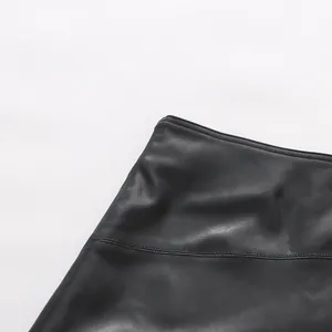 Macro view of black faux leather asymmetric skirt showing fine stitching and texture