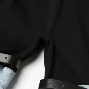 Primer plano detallado de pantalones de retazos negro y mezclilla con cinturón tachonado