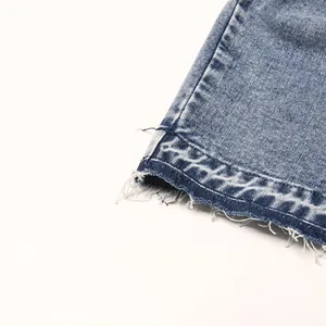 Close-up view of denim skirt frayed hem and decorative geometric embroidery detail.