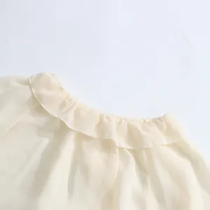 Gedetailleerd overzicht van de elegante ruffelkraag op een lichte crème chiffon damesblouse