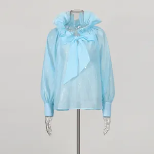 Close-up of light blue mesh blouse with ruffled collar and large bow tie detail