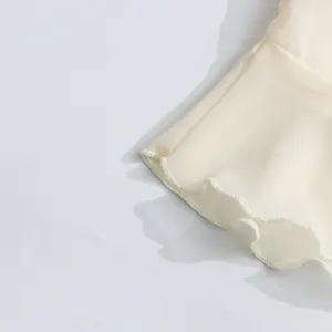 Macro-opname van het verfijnde gelaagde ruffledetail op een lichte crème chiffon blouse.
