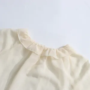 Detailopname van de elegante ruffelkraag op een lichte crème chiffon blouse voor dames