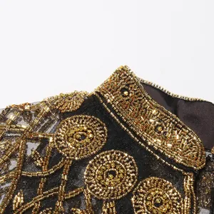 Detailopname van het ingewikkelde handgemaakte gouden kralenwerk op zwart gaasweefsel.
