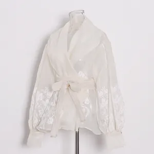 Detail of white vintage sheer court style blouse with floral embroidery and waist tie