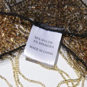 Detail van het materiaallabel op een zware met kralen versierde franje cape jas