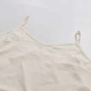Detail of the V-neckline and thin straps of a white romantic style camisole top
