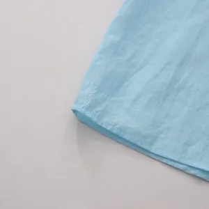 Close-up showing the precise stitching and fabric texture of the light blue blouse hemline.