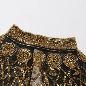 Close-up van ingewikkeld gouden kralenwerk op een zwarte mesh-sjaal.
