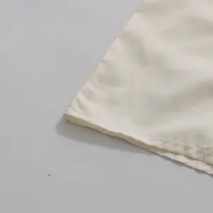 Close-up detail of the clean hemline and high-quality stitching on the cream fabric
