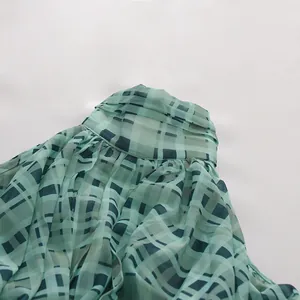 Nahaufnahme von grünem Plaid-Chiffon-Halterhemd mit feinen Kragenfalten und Stoffstruktur