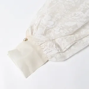 Detailed close-up of vintage floral sheer shirt sleeve with elegant pearl button