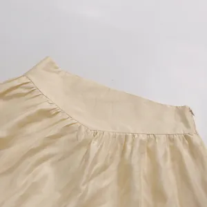 Close-up detail of high-waist A-line skirt featuring pleated fabric and side zipper.