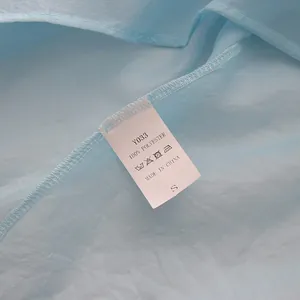 Detail of wash label on light blue mesh shirt showing 100% polyester material