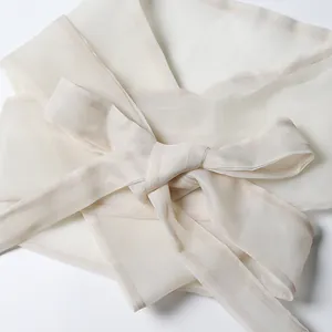 Detailed view of the elegant bow waist-tie on a vintage-style white sheer chiffon dress shirt