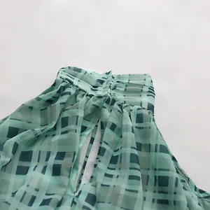 Nahaufnahme des gerüschten Halterneck-Ausschnitts und Karomusters dieser grünen Chiffon-Bluse