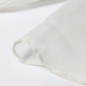 Close-up of fine stitching on the hem of a white vintage court style satin shirt for women