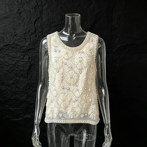 Vue détaillée de la broderie perlée et florale sur un débardeur de luxe blanc raffiné.