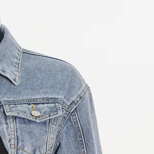 Nahaufnahme einer blauen Jeansjacke mit Schulternähten und Details aus Metallknöpfen.