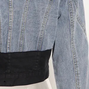 Detaillierte Nahaufnahme einer kurzen Jeansjacke mit stilvollem schwarzem Tailleneinsatz und Naht.