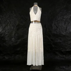 Detail of French white two-piece set featuring halter top and pleated skirt on black rock backdrop