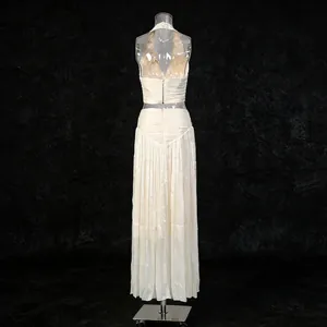Rear view of elegant beige halter neck sleeveless top and pleated maxi skirt set on mannequin.