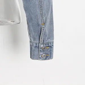Nahaufnahme der Manschette einer Jeansjacke mit Vintage-Metallknöpfen und Ziernähten