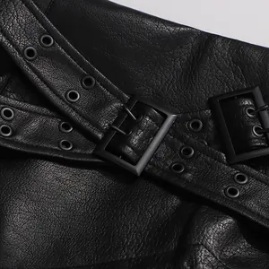 Vue macro d'une jupe en similicuir noir avec ceinture décorative et boucles.