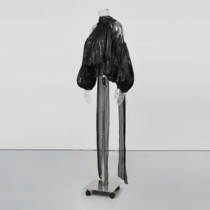 Vue détaillée d'un haut noir brillant à manches bouffantes et épaules dénudées.