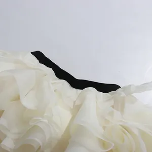 Detailansicht eines weißen gerafften Organza-Rocks mit schwarzem Samtbund und Falten.