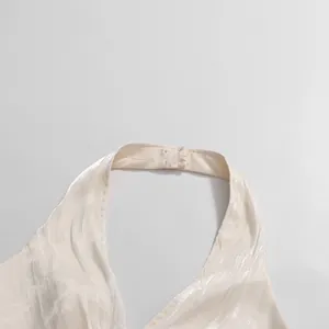Detailed view of cream halter neck top with elegant pleated shimmering fabric texture