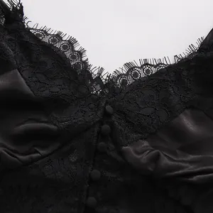 Dettaglio ravvicinato del delicato pizzo nero e del tessuto satinato su un top sottoveste con scollo a V