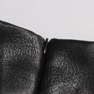 Gros plan sur la fermeture éclair invisible et la texture d'une jupe en cuir noir.