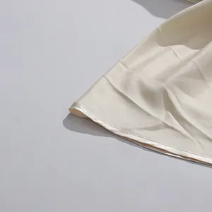 Detailansicht eines eleganten elfenbeinfarbenen Satinkrock-Saums mit feiner Verarbeitungsqualität